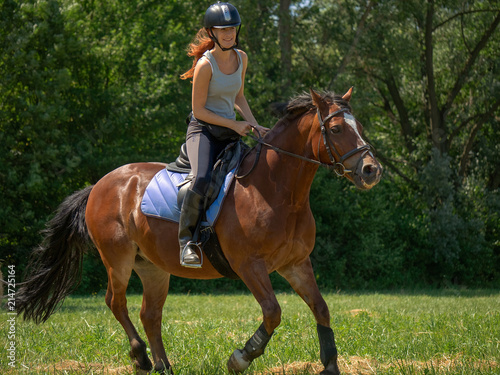 Frau model Reiterin reitet auf Pferd auf Wiese in der Natur bei Sonnenschein im Sommer