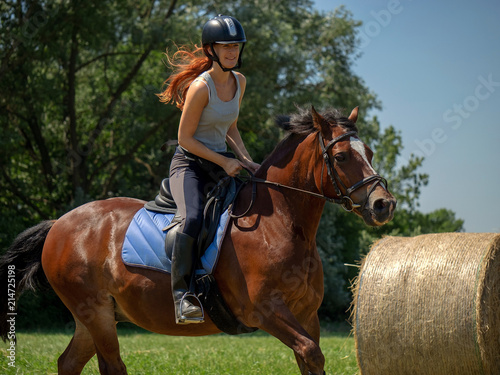 Frau model Rieterin reitet auf Pferd auf Wiese in der Natur bei Sonnenschein im Sommer
