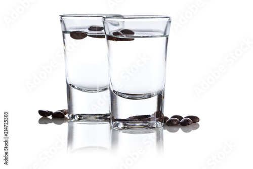 Two shot glasses with Italian Sambuca hard liquor surrounded by coffee beans isolated on white background