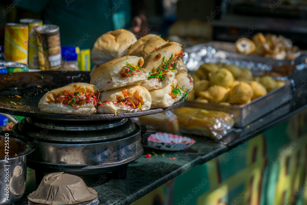 Fototapeta premium Mumbai Street Food. Najważniejsza przekąska nazywa się „Dabeli”, a przekąska w tle to „Vada Pav”
