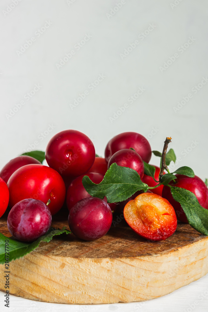 Fresh red plum with leaves on a wooden light background Fresh red plum with leaves on a wooden light background