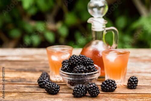 Fresh blackberries and liqueur on wooden table