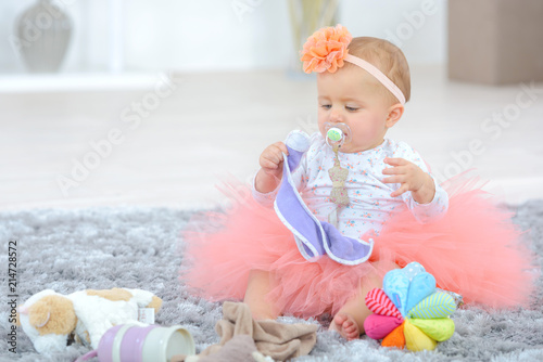 Baby dressed in tutu playing on rug