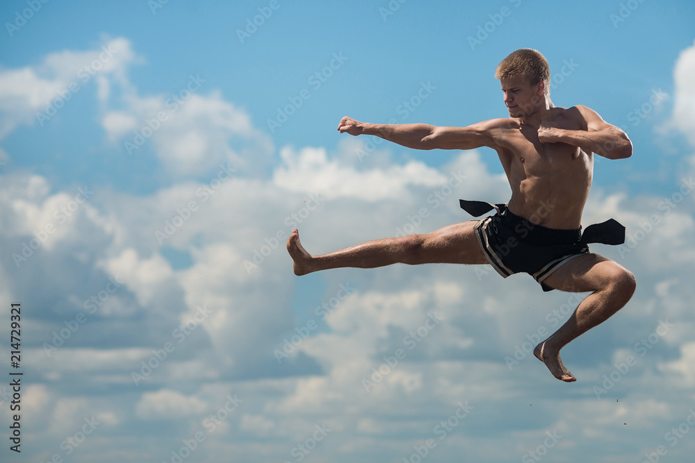 Man flying kick in sky background
