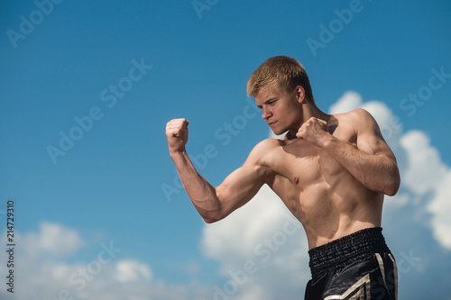 Obraz na plátně Muscular male fighter training. Boxer trains in the open air