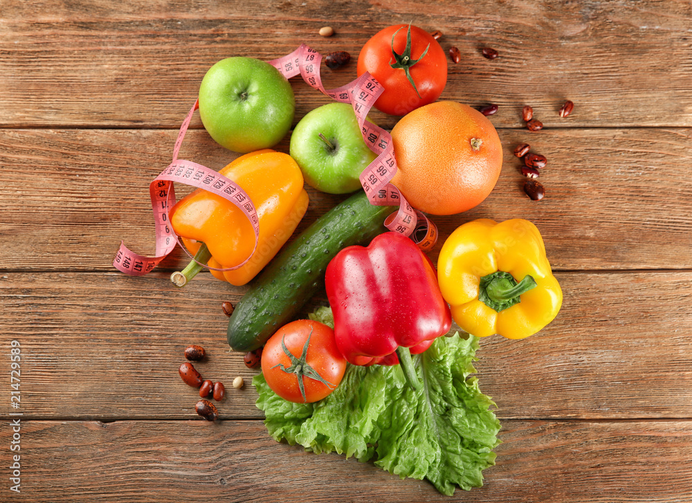 Vegetables, fruits and measuring tape on wooden background. Diet food Vegetables, fruits and measuring tape on wooden background. Diet food