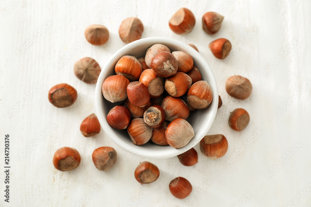 Bowl with unpeeled hazelnuts on white wooden background Bowl with unpeeled hazelnuts on white wooden background