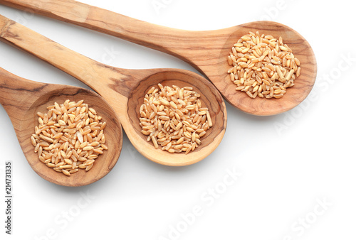 Spoons with wheat grains on white background