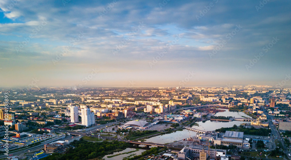 Aerial drone panoramic view of Chelyabinsk city and embankment of Miass river, smoking pipes on the background and blurred horizon, city with bad ecological situation, Russia