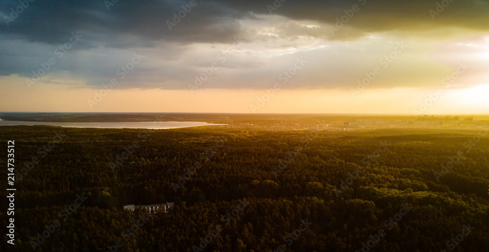 Fototapeta premium Aerial drone view of residential area with huge city forest, capital of South Ural in sunny evening after rain, park of culture and recreation on the foreground, Russia