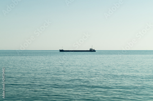Large ship in the middle of the sea near the coast leading towards the port. © Igli