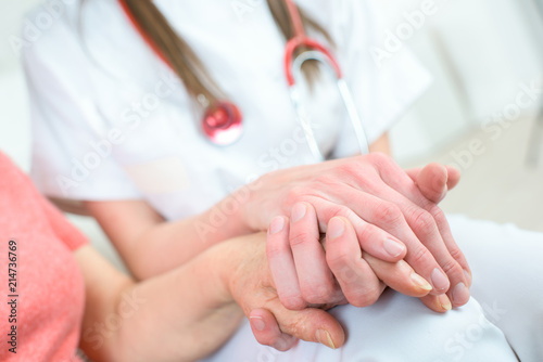 nurse holding hand of senior woman in wheel chair