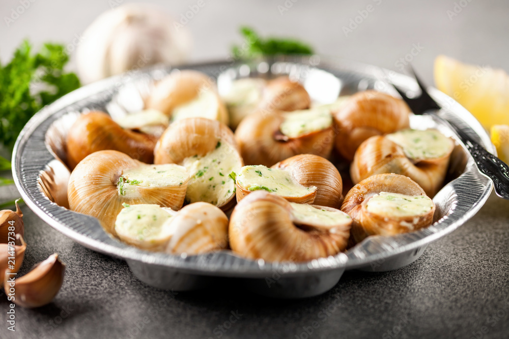 Escargots de Bourgogne - Snails with herbs butter on gray background. Selective focus Escargots de Bourgogne - Snails with herbs butter on gray background. Selective focus