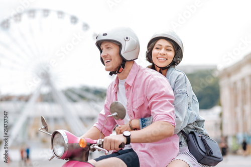 Hug me. Enthusiastic merry man conducting motorbike and woman smiling