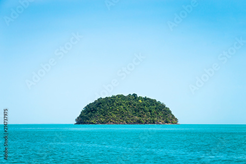 Round green island. Seascape with rock island in the tropical sea, Thailand. Blue clear sky.