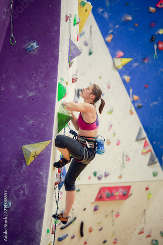 Photo of young athlete climbing up purple wall