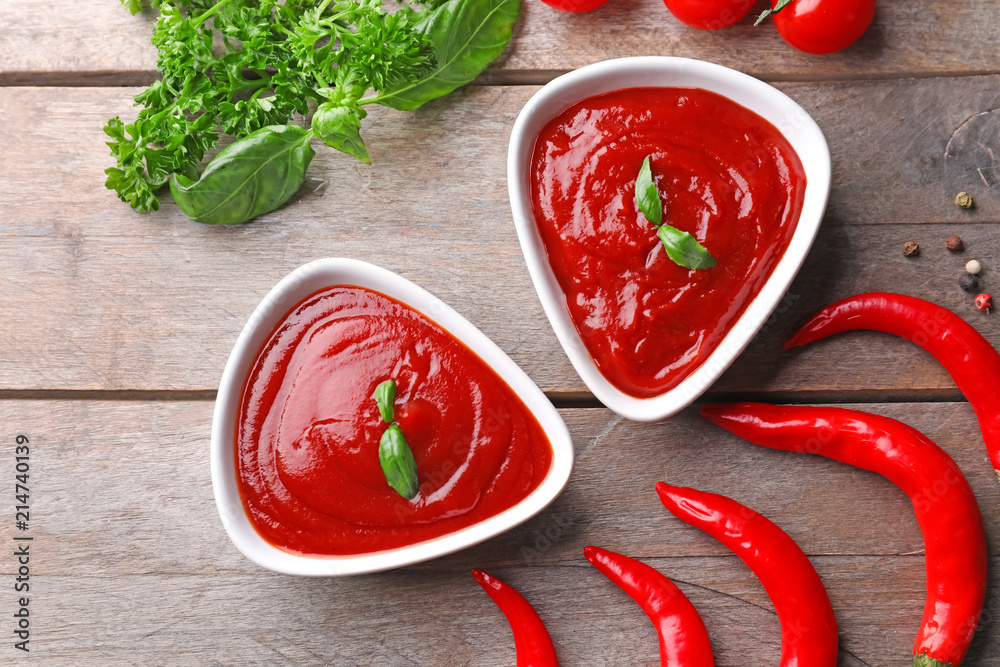 Composition with delicious tomato sauce and chili peppers on wooden table Composition with delicious tomato sauce and chili peppers on wooden table