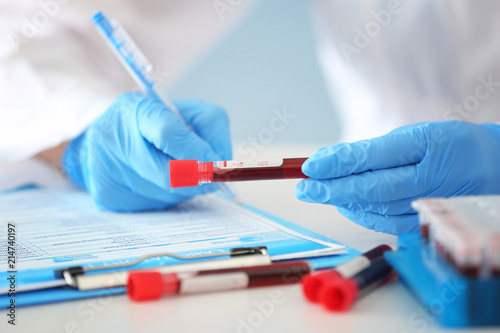 Woman working with blood sample in test tube at table