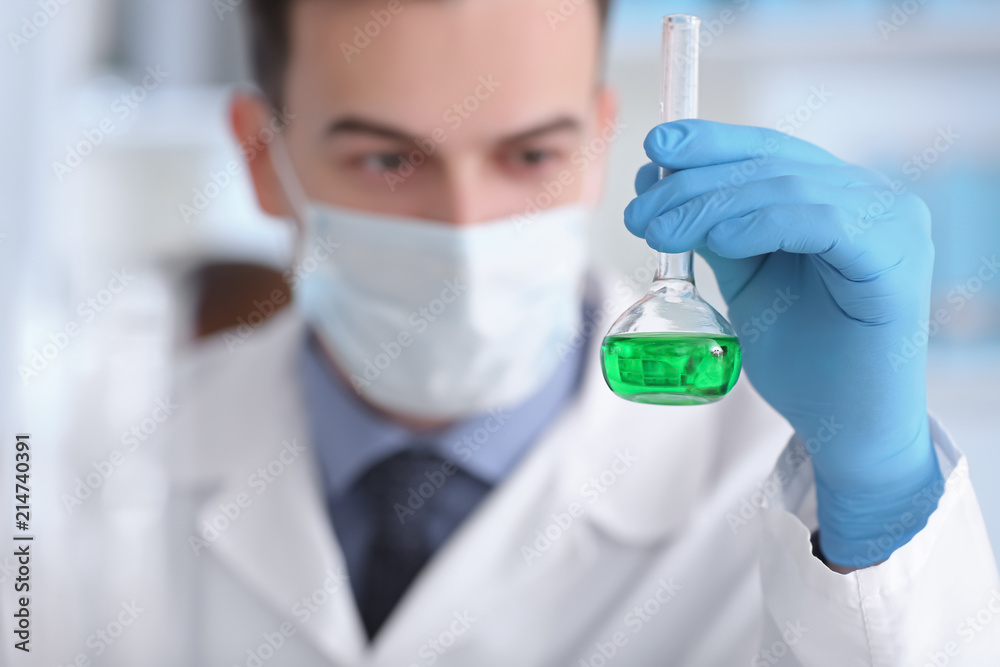 Scientist holding test flask with sample in laboratory Scientist holding test flask with sample in laboratory