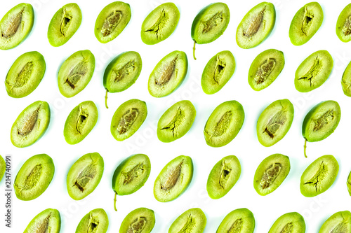 Bright top view pattern of fresh green olives cut in half on white background. Shot from above of multiple olives