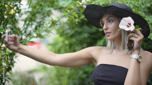 Young stylish beautiful woman in hat does selfie. Female using a smart phone