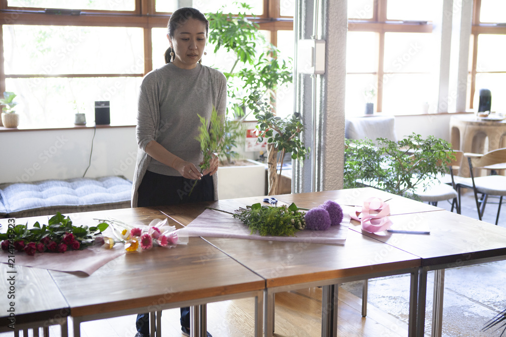 お客様にお渡しする花束を真剣に丁寧に作り上げる女性店員 お客様にお渡しする花束を真剣に丁寧に作り上げる女性店員