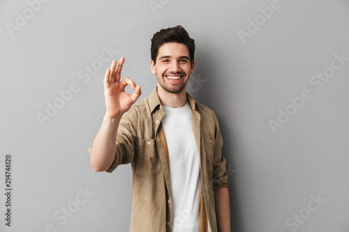 Portrait of a happy young casual man showing ok gesture photo