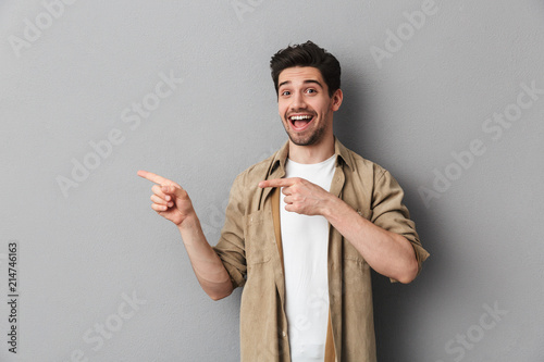 Portrait of a happy young casual man pointing away photo