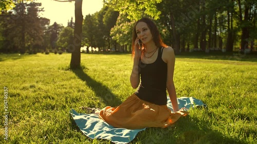 Front view of a woman sit towards camera talk during a phone call outdoors in the park. Slo-mo static shot. photo