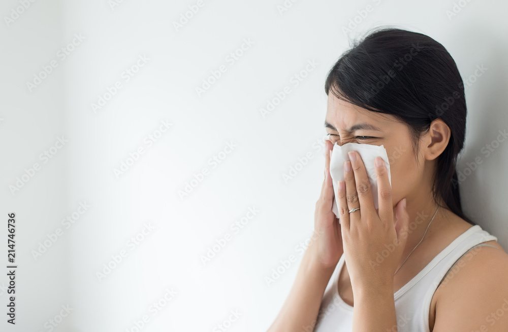 Young asian woman with cold blowing and runny nose in home,sick woman sneezing,Concept of health,Close up and selective focus Young asian woman with cold blowing and runny nose in home,sick woman sneezing,Concept of health,Close up and selective focus