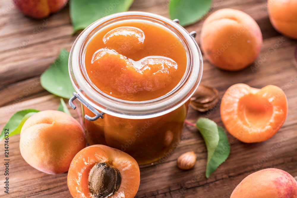 Apricot jam and ripe apricots on the table.