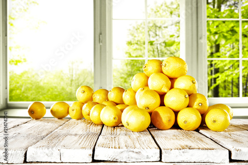 fresh yellow lemon on desk and window background with summer garden. Free space for your glass. 