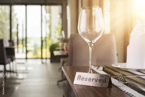 Reserved sign on a table in restaurant. Empty glasses set in restaurant