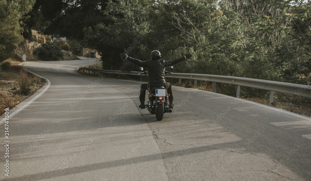 Man raising arms up while rides his black motorcycle.