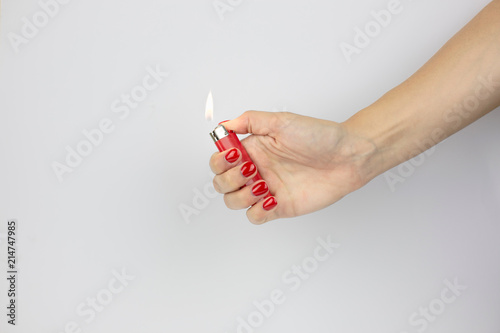 red lighter with fire in woman's hand with red nails isolated on white background