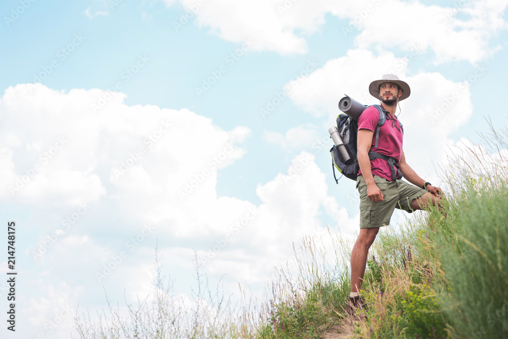 male hiker in hat with backpack and tourist mat