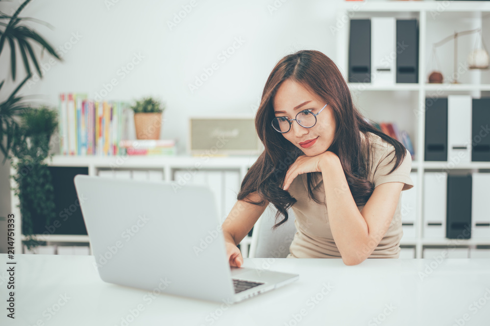 Happy young businesswoman with glasses working on computer laptop in home office Happy young businesswoman with glasses working on computer laptop in home office