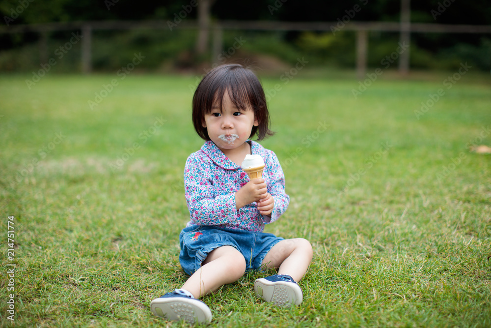 baby girl sitting on summer meadow and eating icecream baby girl sitting on summer meadow and eating icecream