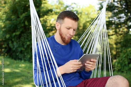 Young man reading book in hammock outdoors
