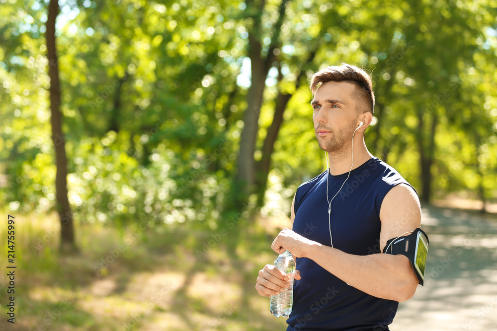 Sporty man with bottle of water in park Sporty man with bottle of water in park
