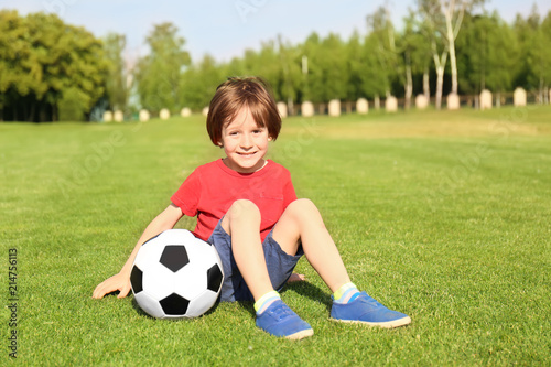 Cute little boy with soccer ball in park on sunny day