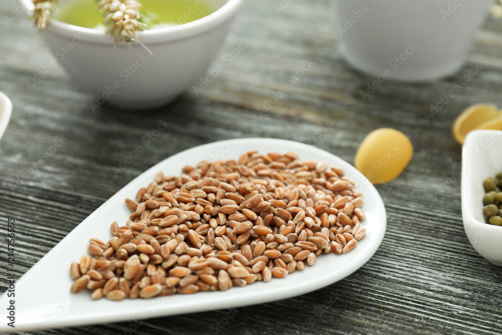 Plate with wheat grains on wooden table Plate with wheat grains on wooden table