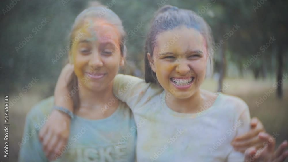 Two teenage girls smeared with colored powder Holi sprinkle water in the summer Park in Slow motion Two teenage girls smeared with colored powder Holi sprinkle water in the summer Park in Slow motion