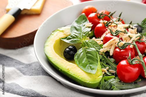 Tasty salad with avocado in bowl on table, closeup