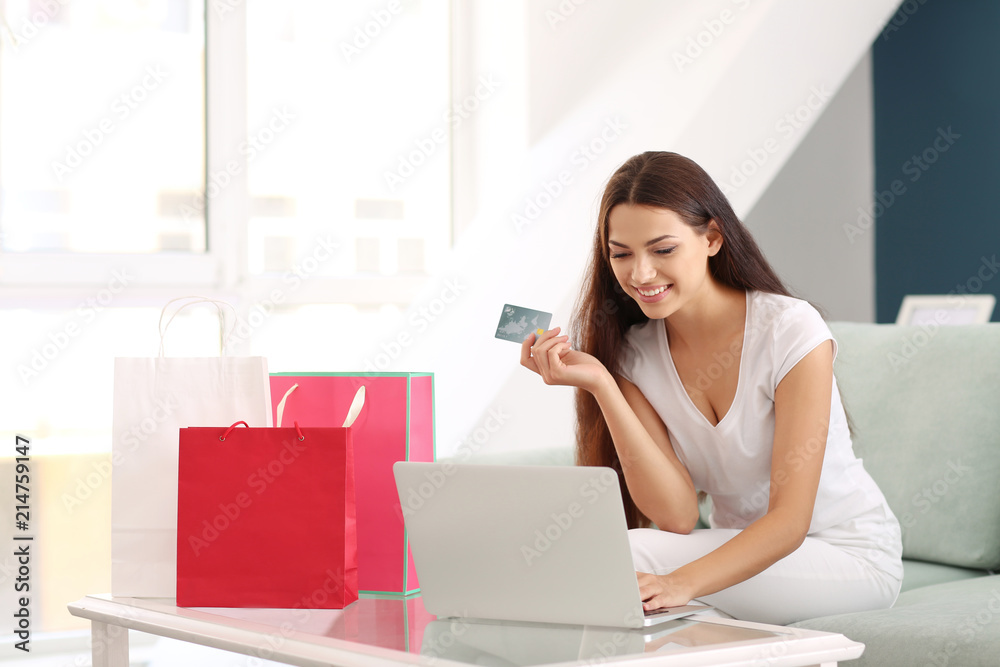 Young woman shopping online with credit card and laptop at home Young woman shopping online with credit card and laptop at home