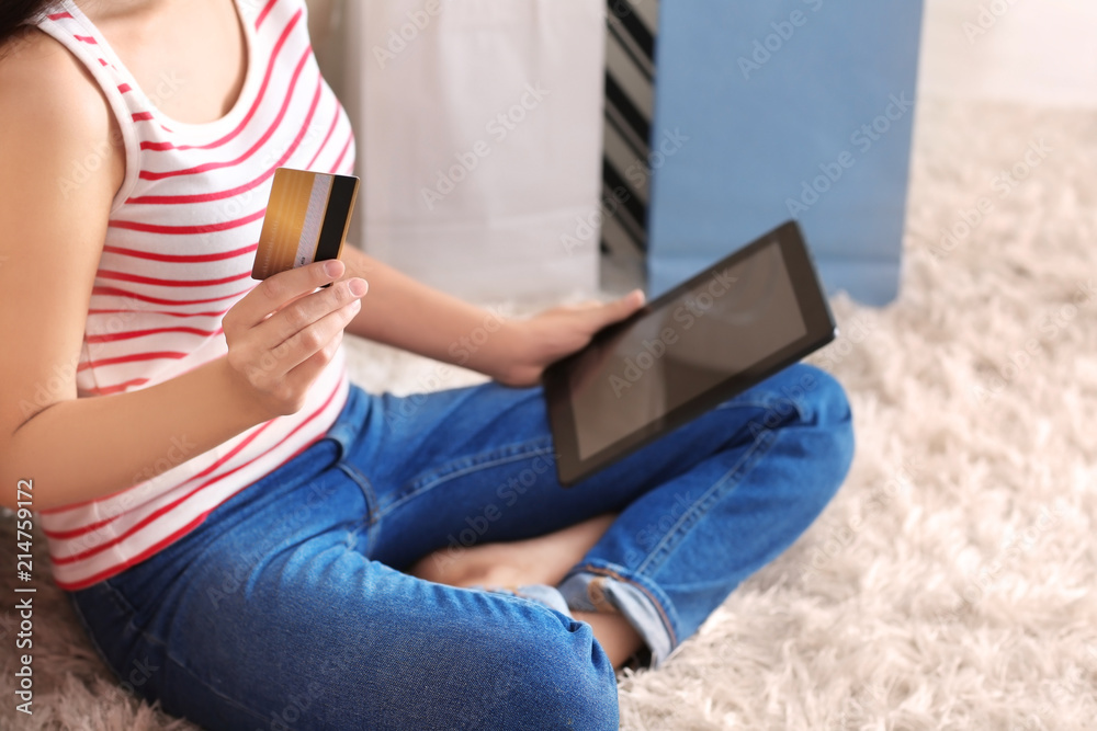 Naklejka premium Young woman shopping online with credit card and tablet PC at home