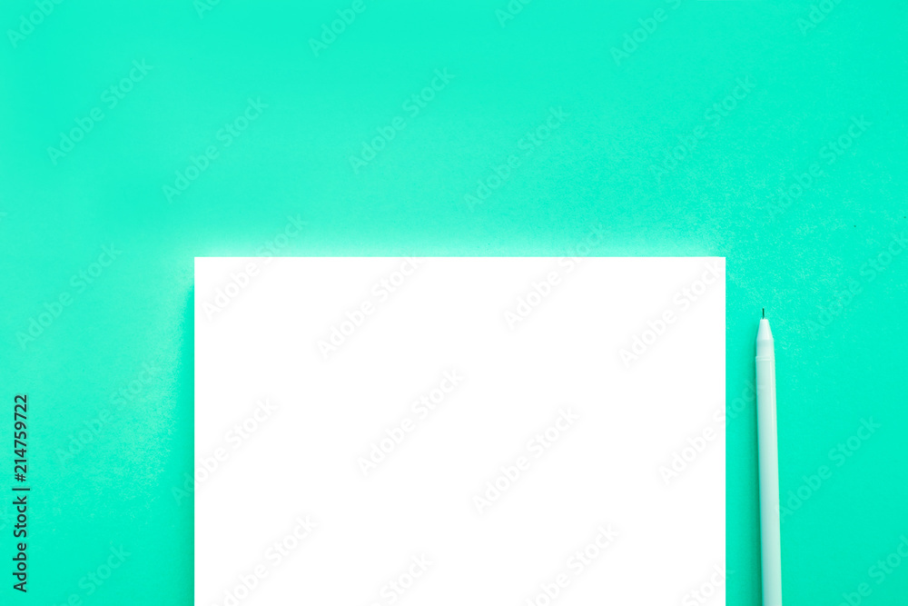 Beautiful office stationery flatlay with ruled notebook and white pen on the bright desk with turquoise background. Beautiful office stationery flatlay with ruled notebook and white pen on the bright desk with turquoise background.