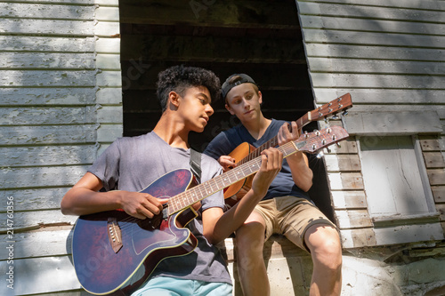 Two Teeenage Boys Jamming with Guitars in the barn