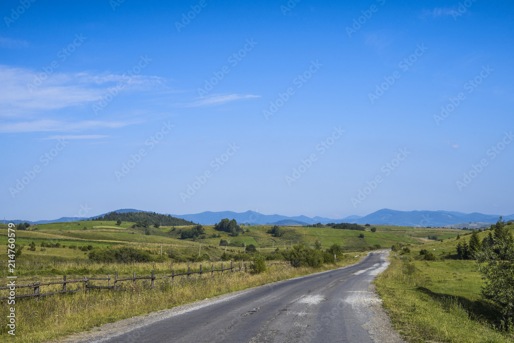 old road through a field in the mountains on a sunny afternoon