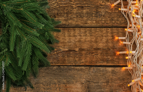 Beautiful bright Christmas lights with fir branches on wooden background